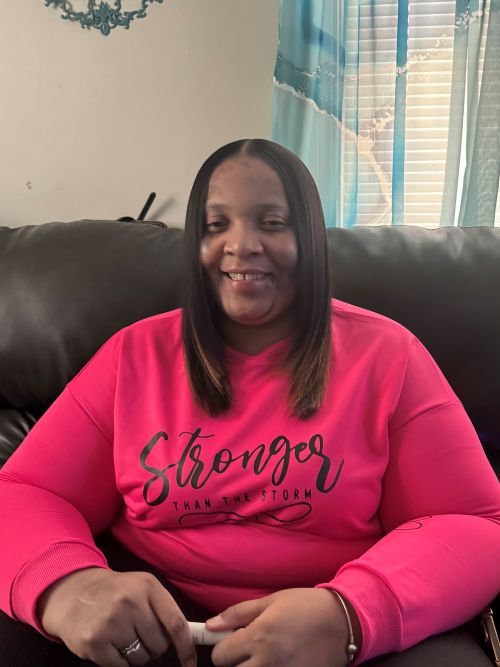 Shonika smiling with a pink sweater on that says stronger than the storm 